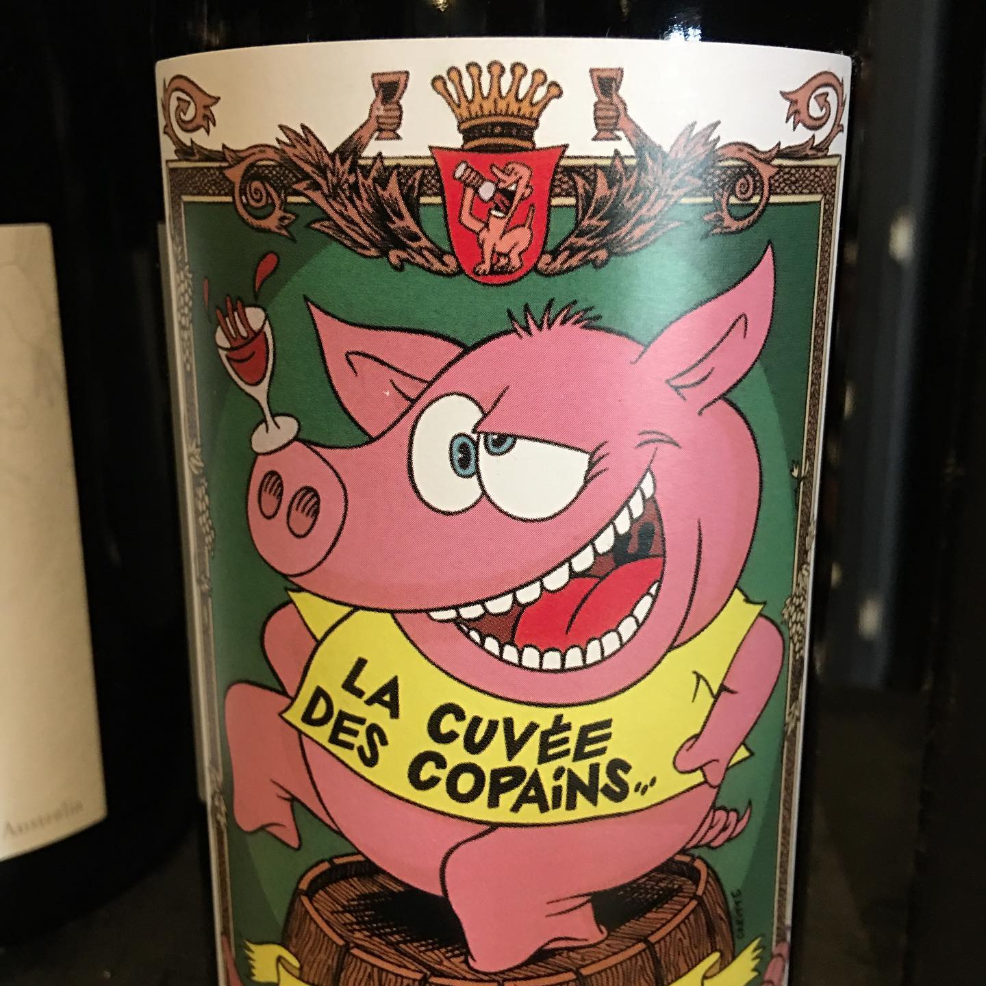 Close-up of a quirky illustrated wine label with a cartoon pig raising a glass