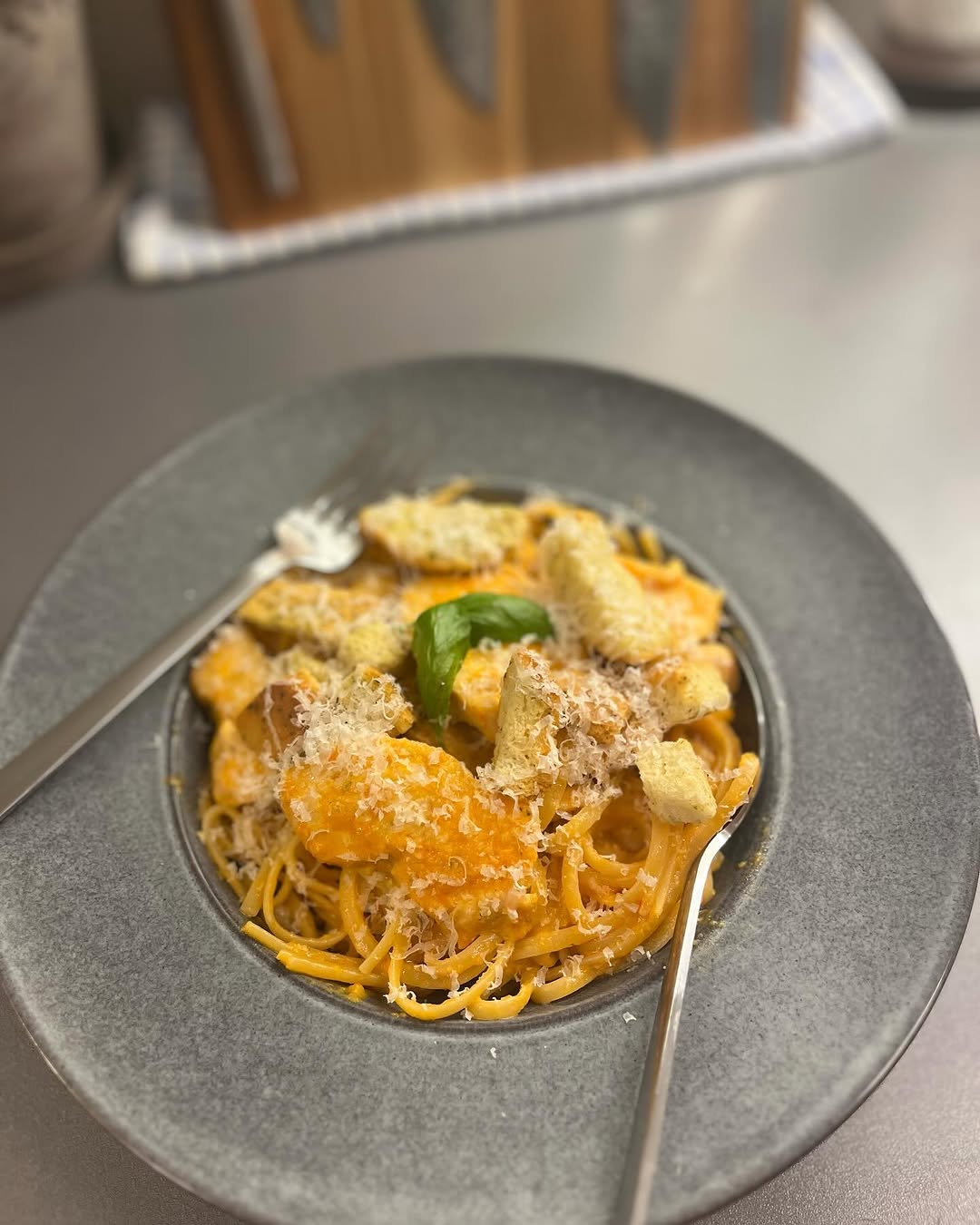Linguine pasta with pumpkin sauce, croutons and parmesan on a grey plate