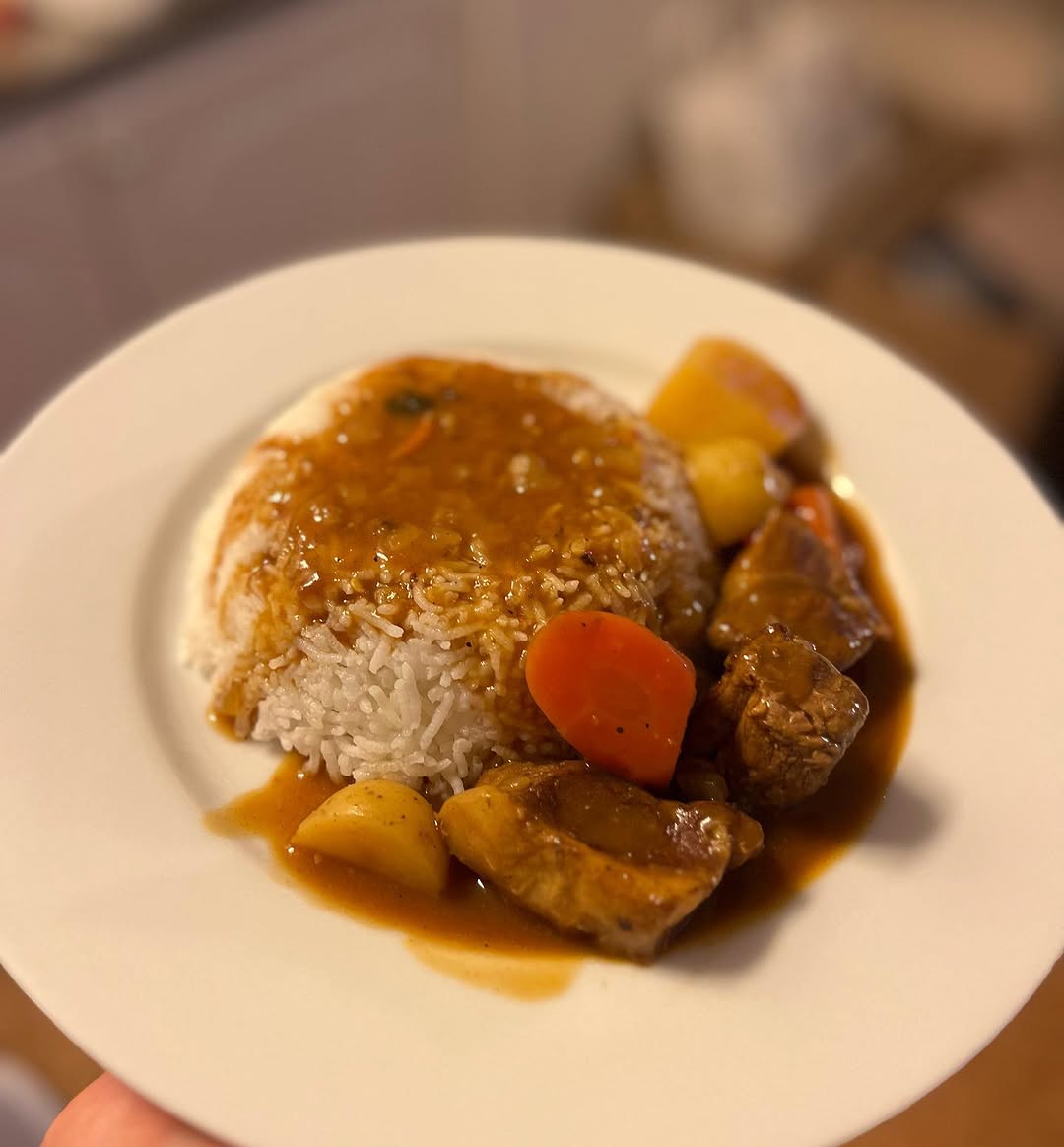 Japanese beef curry with carrots and potatoes over steamed rice on a white plate