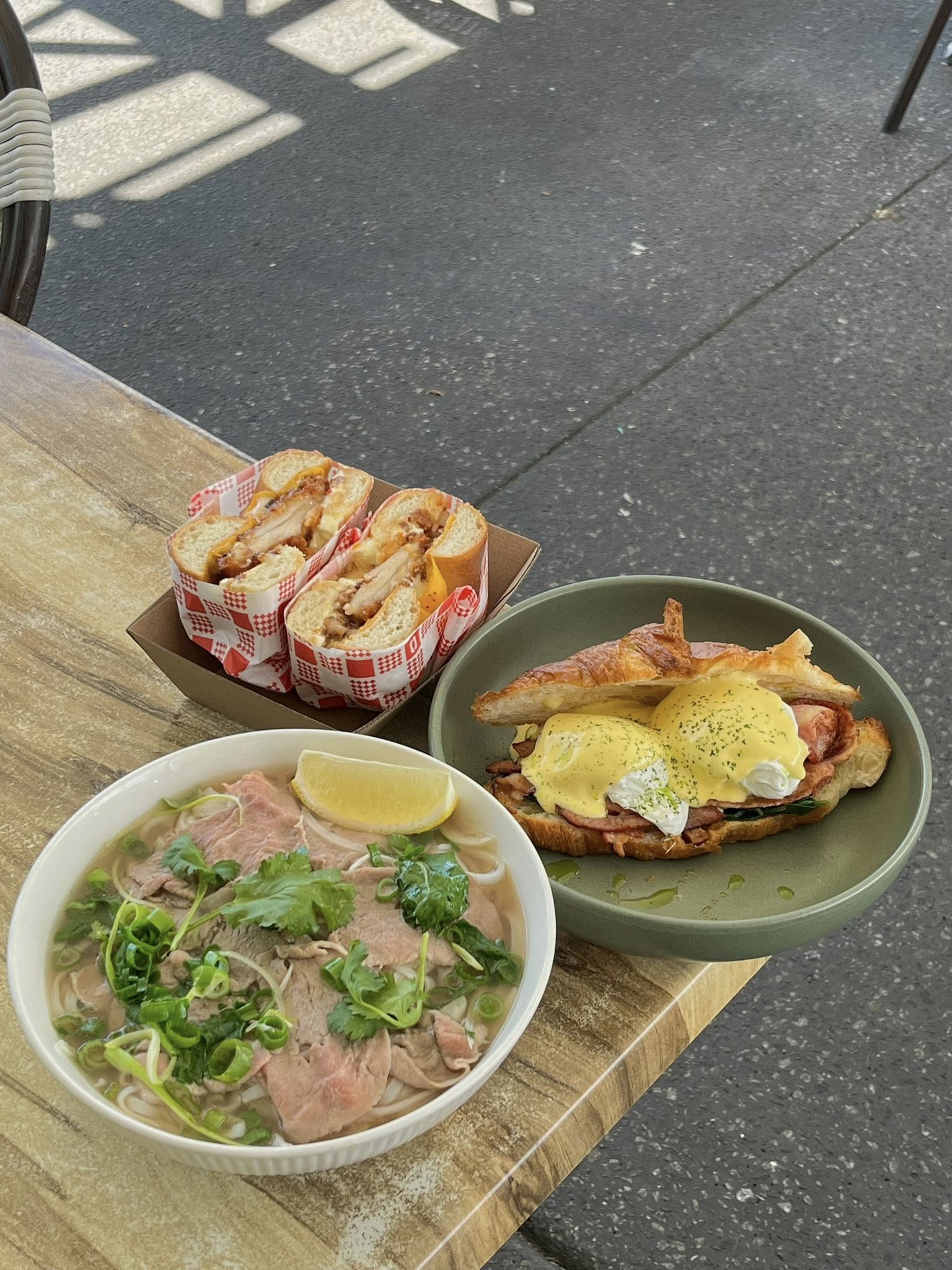 Little Elm Cafe food spread — pho noodle soup, eggs benedict on croissant, and a toastie sandwich served at the cafe