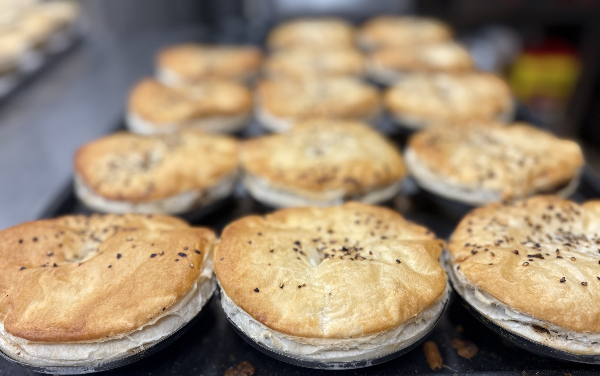 Tray of golden baked savoury pies fresh from the oven at Manly Bakery