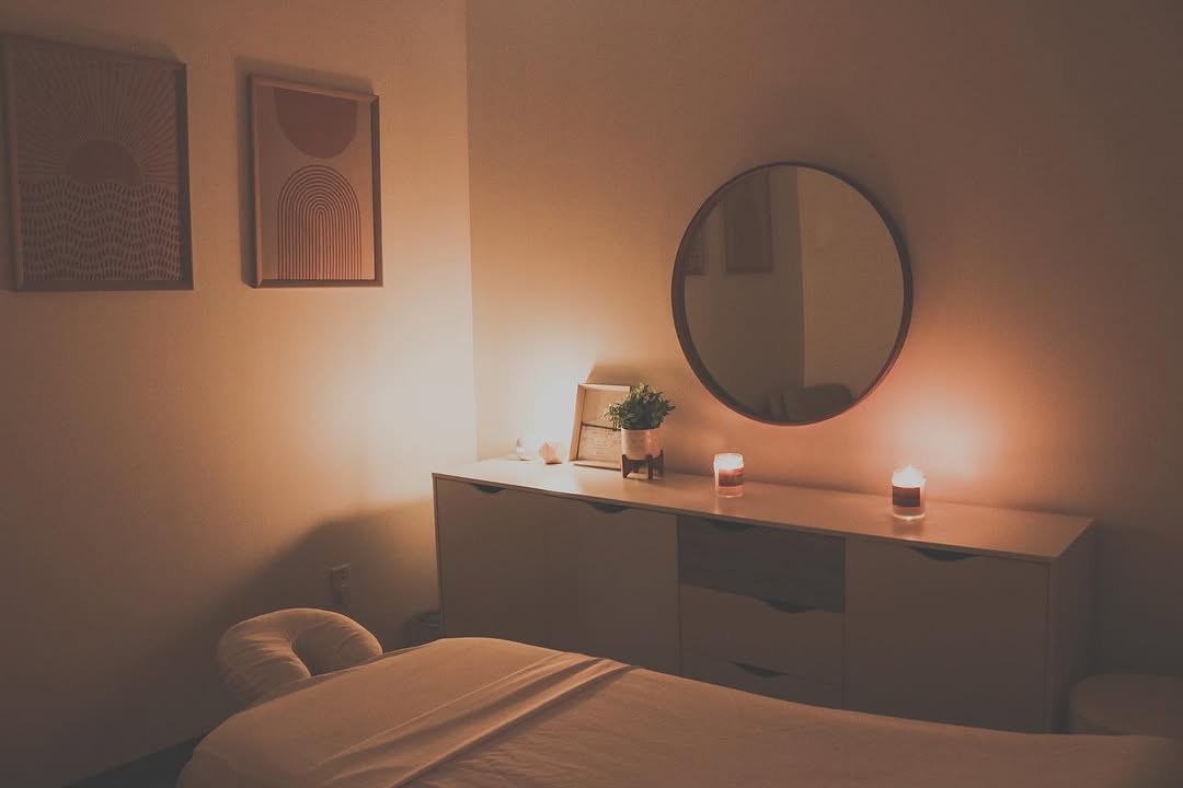 Warm candlelit massage therapy room with round mirror and art prints at Zen Tara Mentone