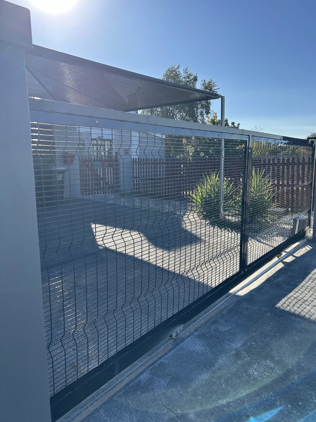 Vista Fencing — galvanised steel sliding driveway gate installation in bright sunlight