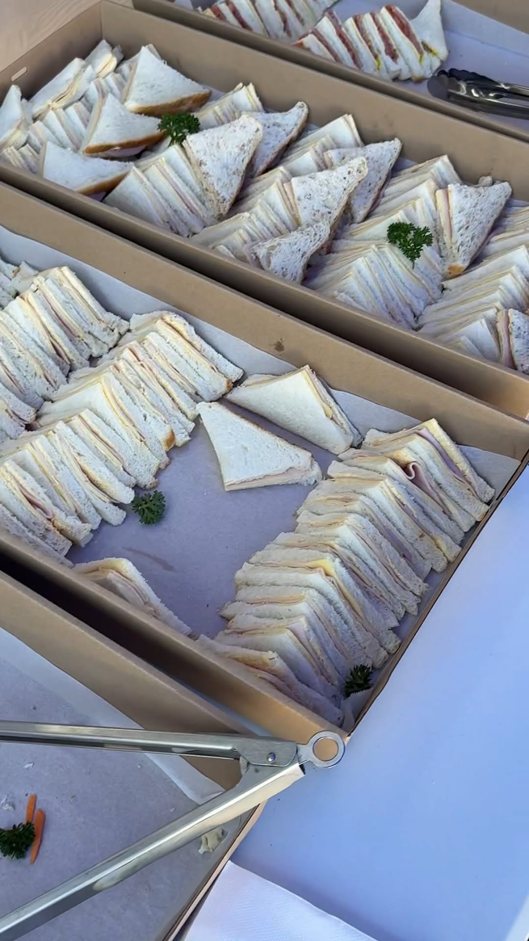 Multiple trays of neatly arranged sandwiches presented at a catering buffet