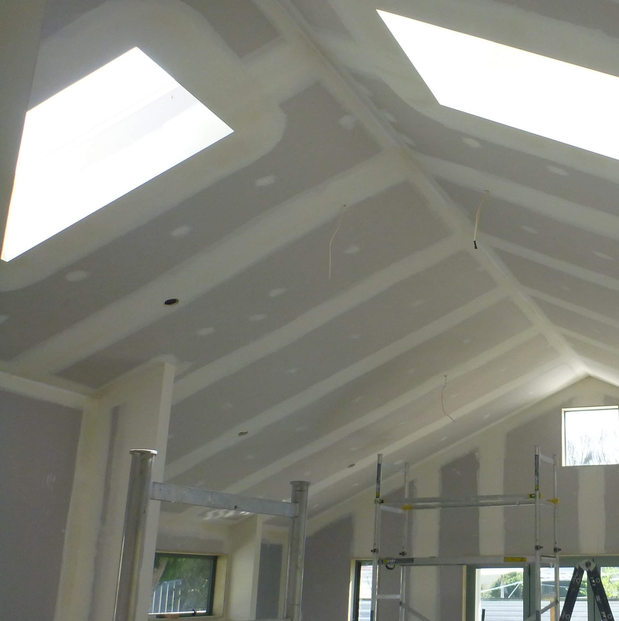 Plasterboard installation on a vaulted ceiling with skylights during a building project