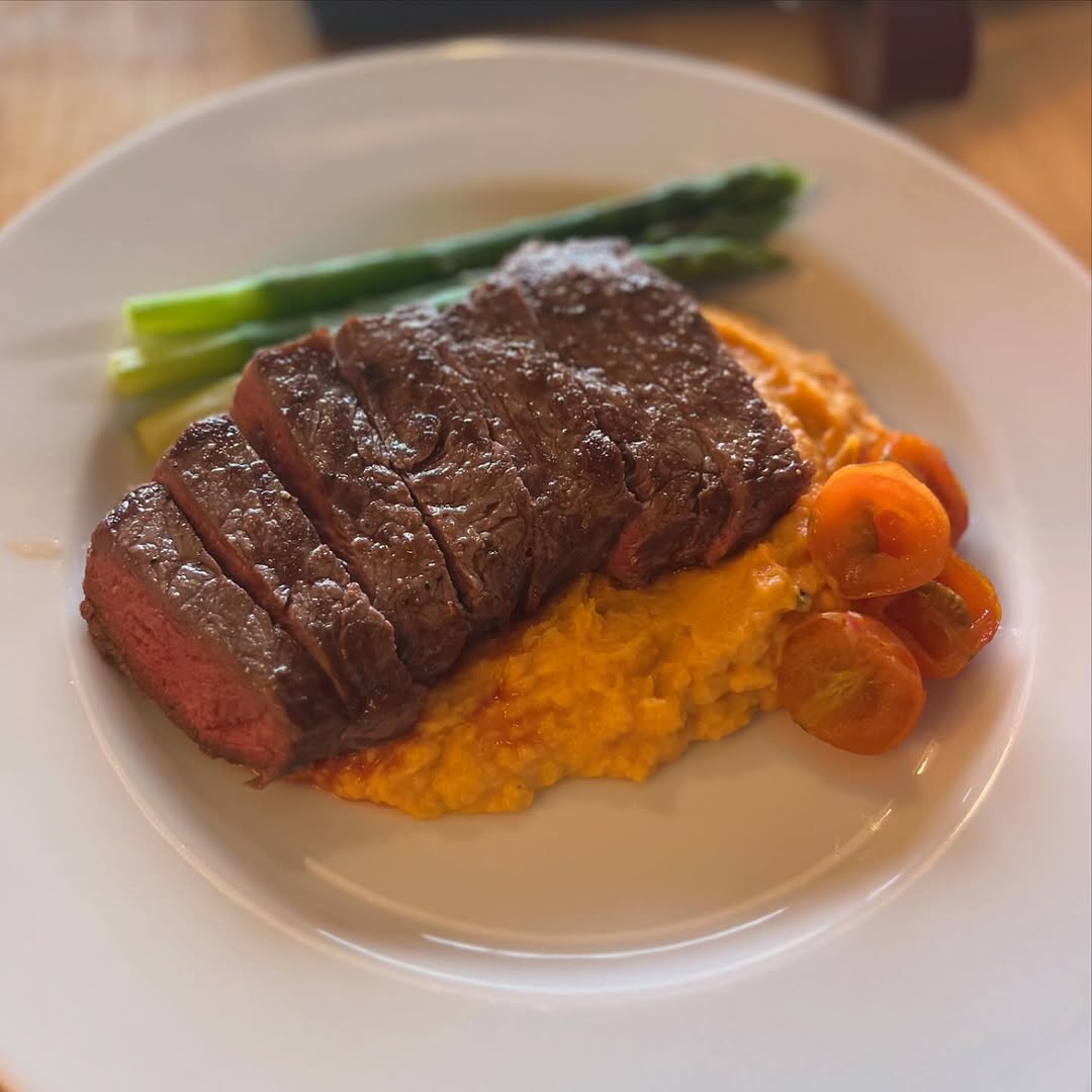 Sliced beef steak on sweet potato mash with asparagus spears
