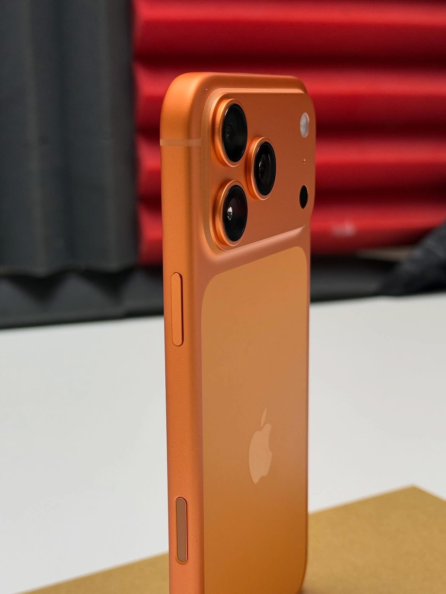 Close-up of an orange iPhone showing camera module and Apple logo