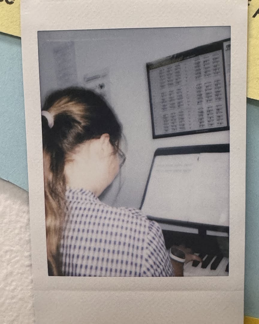 Student playing a keyboard during a lesson, seen from behind