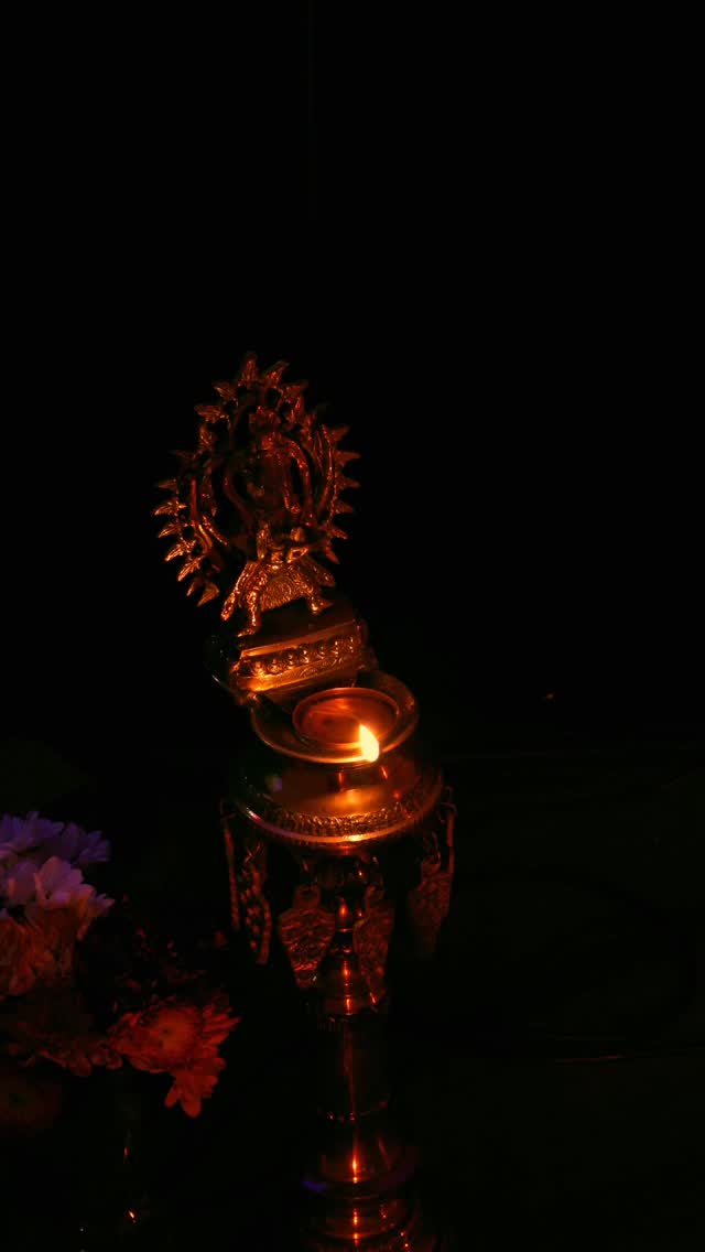 Brass diya oil lamp glowing warmly with flowers, representing devotion and spiritual atmosphere