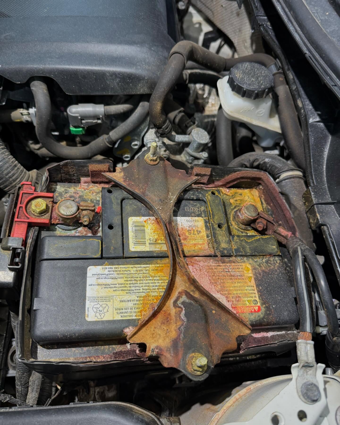 Close-up of an engine bay during a repair, showing battery and engine components