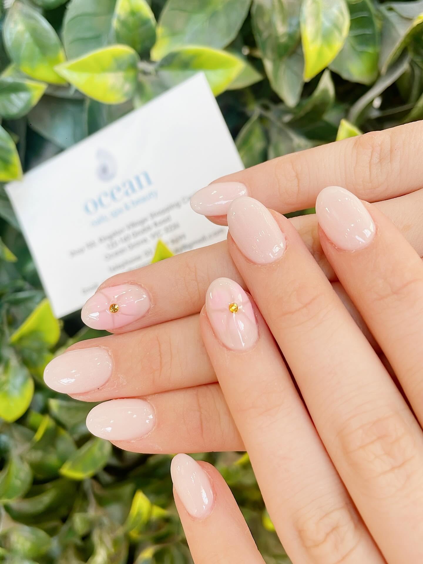Nude blush gel nails with gold accent details, displayed with Ocean Nails business card
