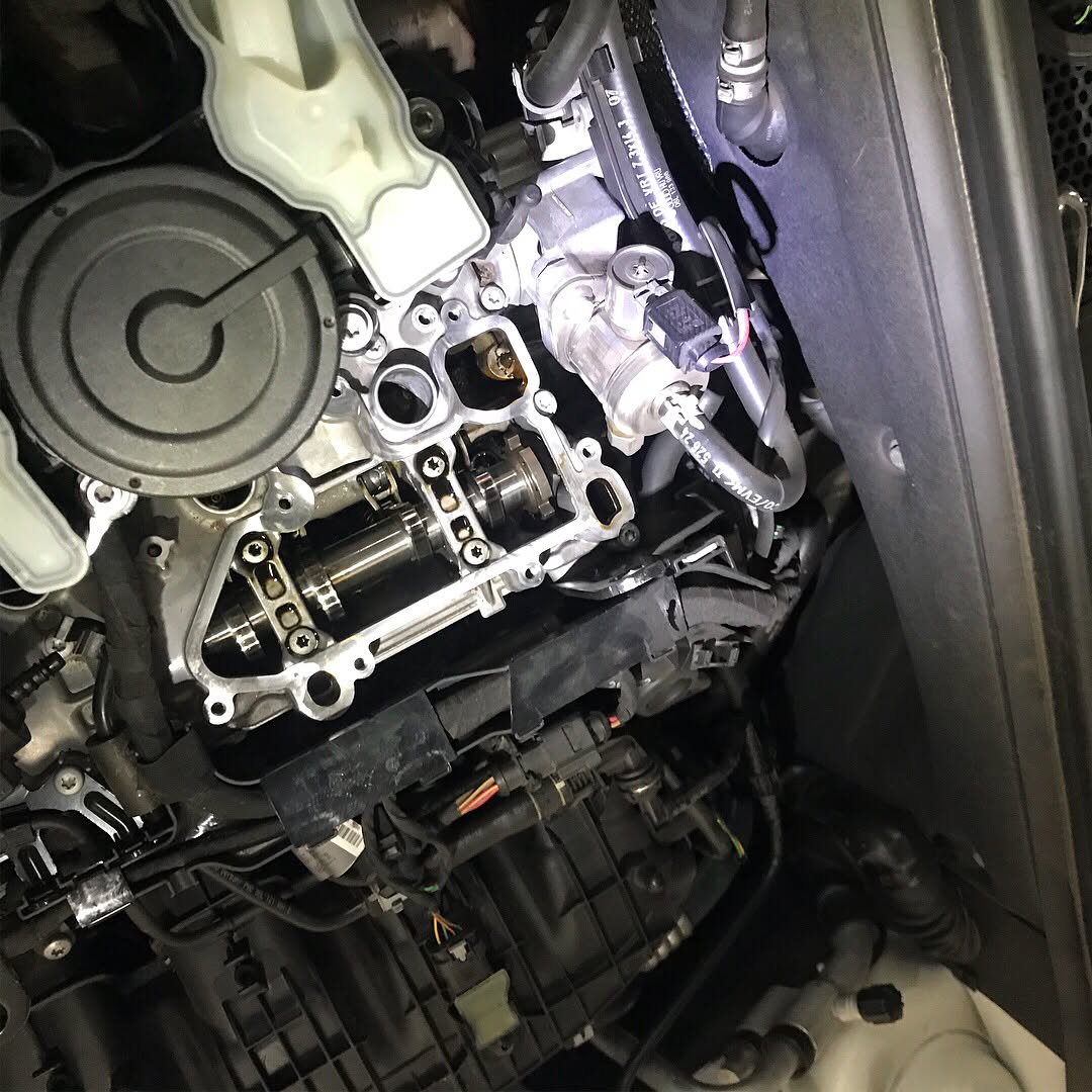 Close-up of a car engine bay with valve train components exposed during mechanical repair