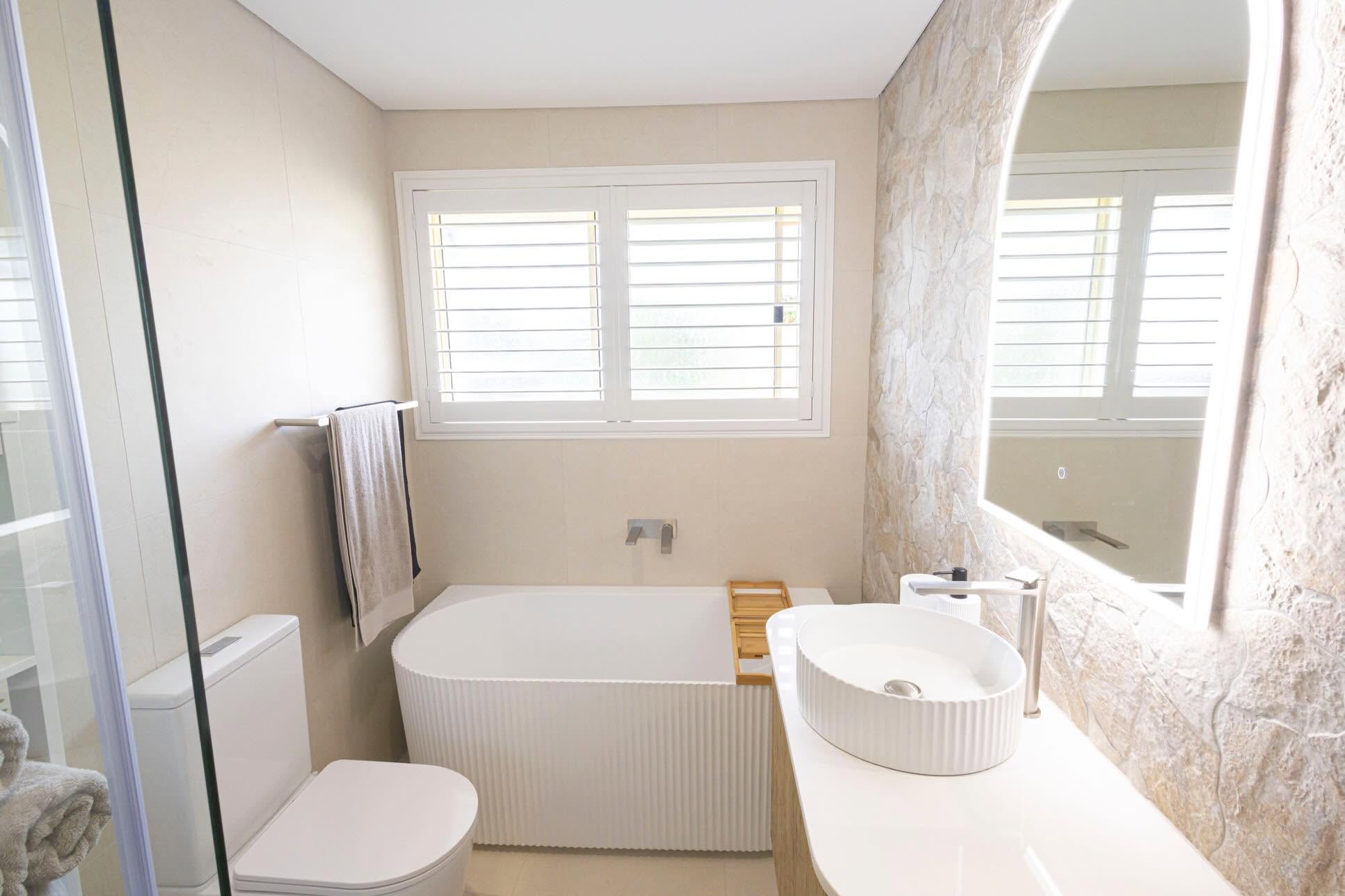 Completed bathroom renovation with freestanding bath, vessel sink and tiled walls – Wollondilly Tiles
