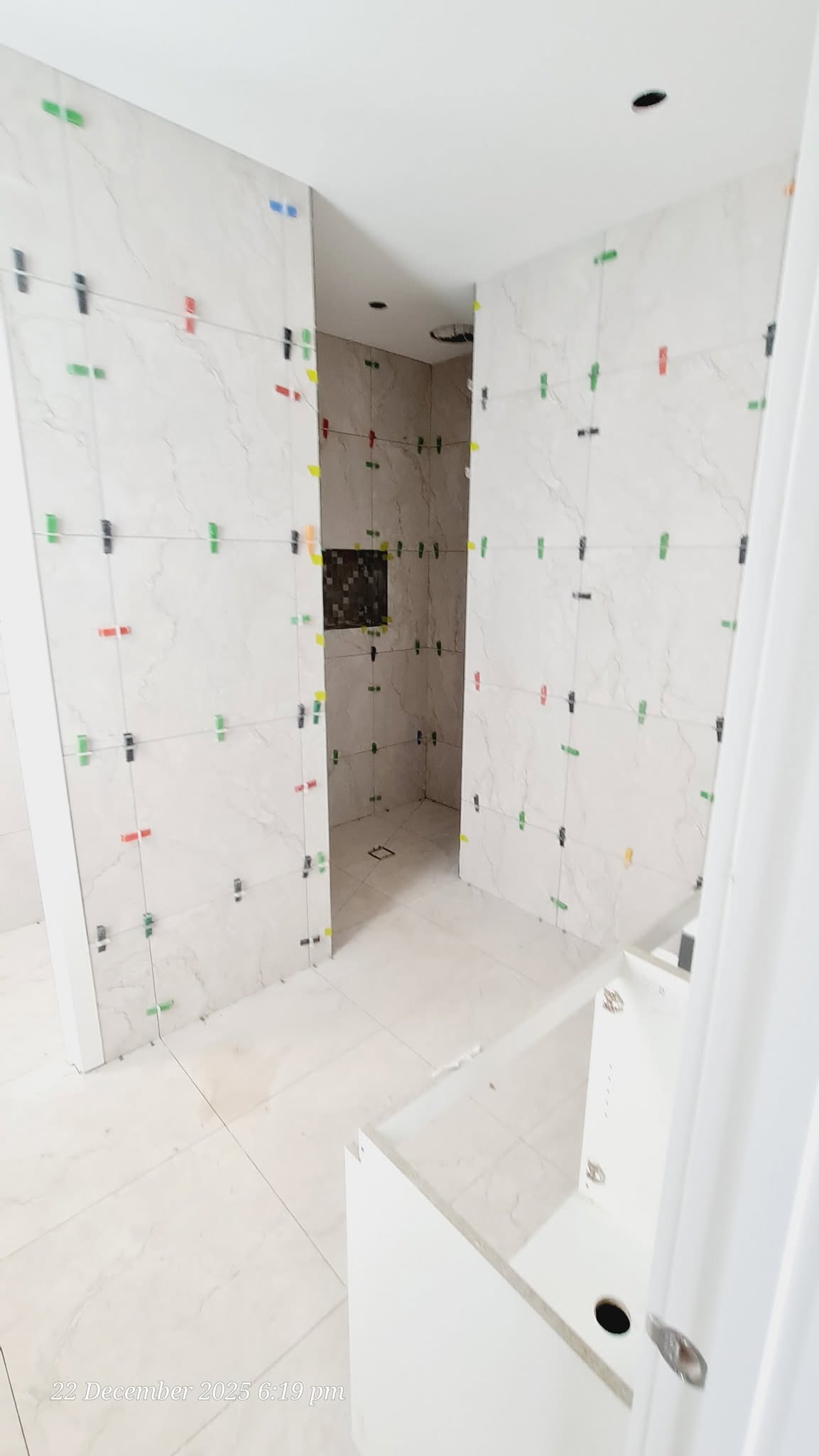 Large walk-in shower area fully tiled in white marble-look porcelain
