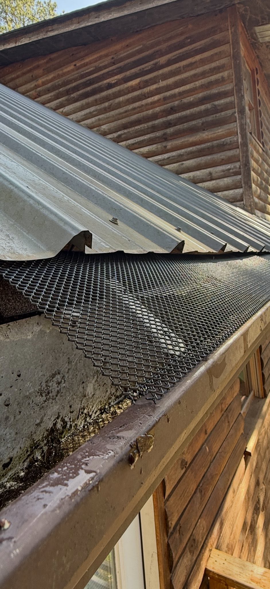 Close-up of newly installed metal mesh gutter guard on a corrugated iron roof