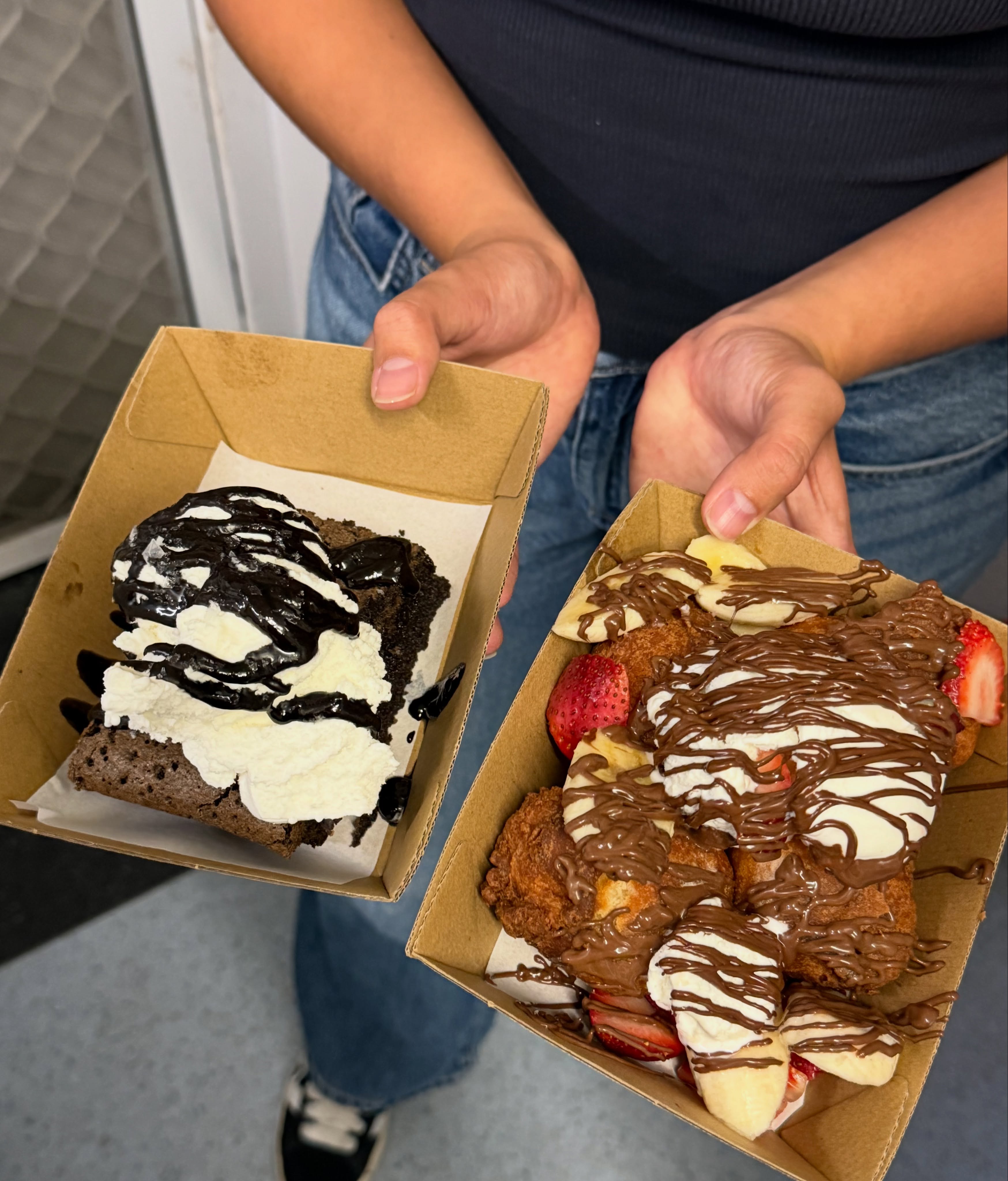 Two takeaway boxes with a chocolate brownie and chocolate-drizzled pastries from Lenaya Baked Goods cafe