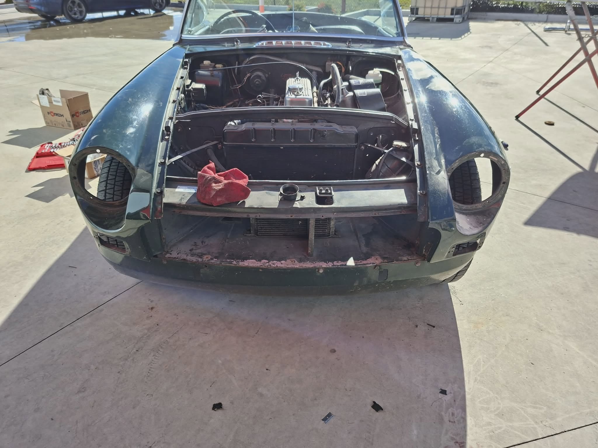 British Racing Green MGB with bonnet open showing engine — April Motors workshop