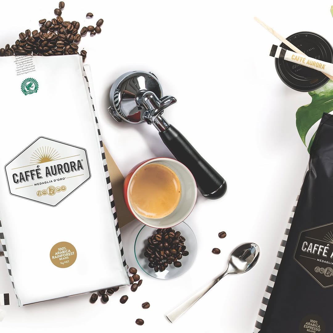 Caffè Aurora branded coffee bags, portafilter, and freshly pulled espresso shot with coffee beans