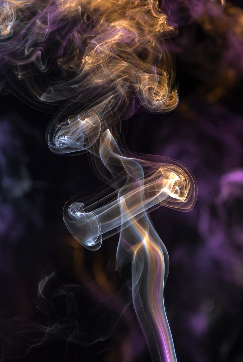 Multiple candles burning in a sacred ritual space with purple smoke and soft bokeh light