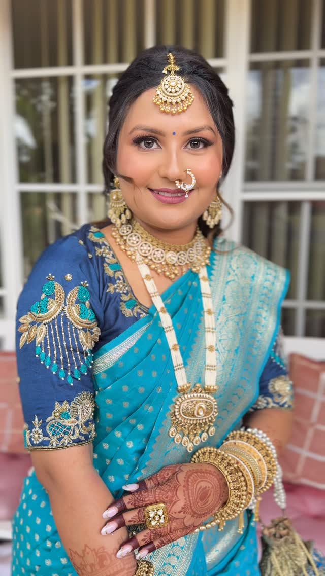 Bridal makeup with maang tikka and nath on a client in a teal embroidered saree