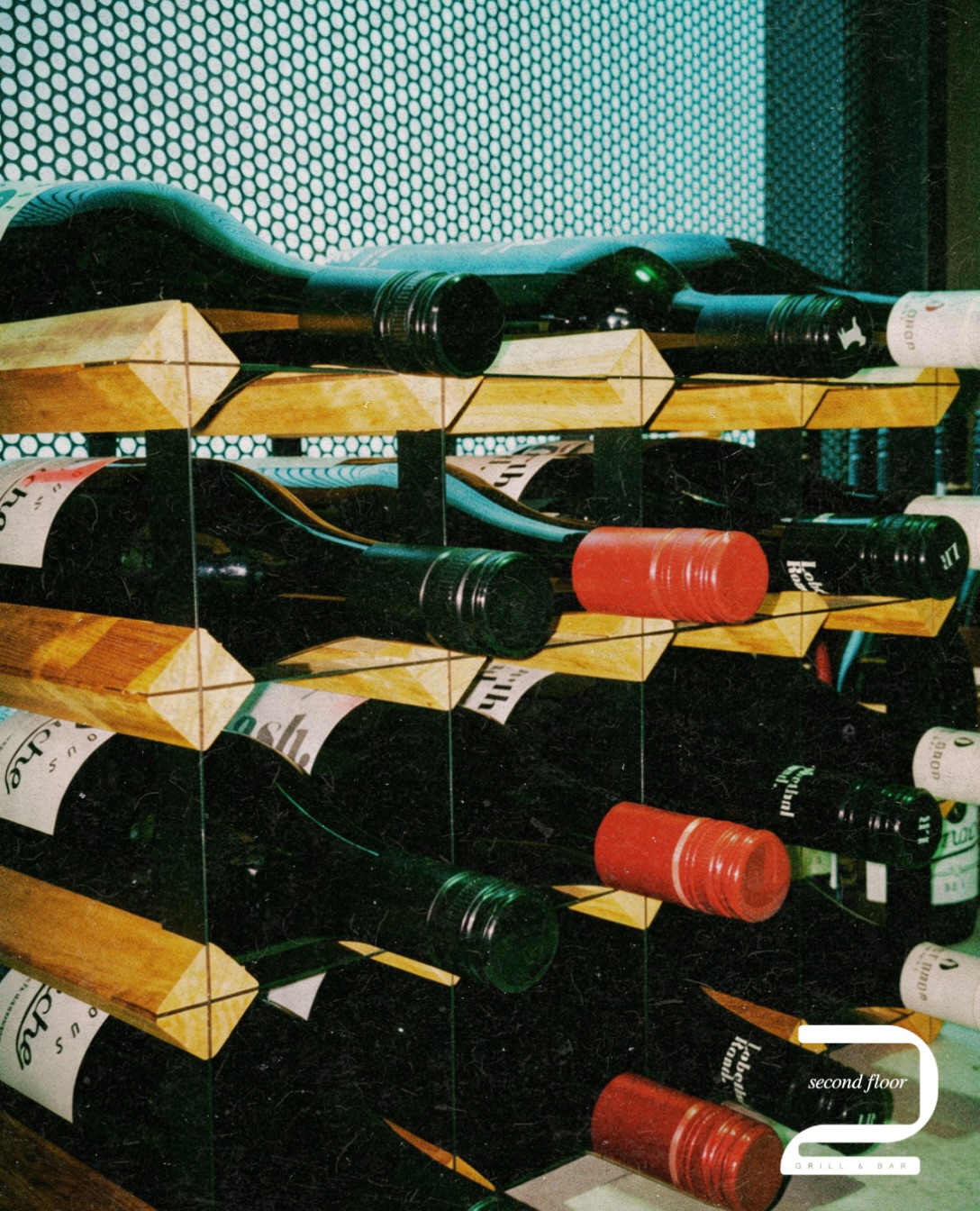 Bottles of wine resting in a timber and glass rack at the bar