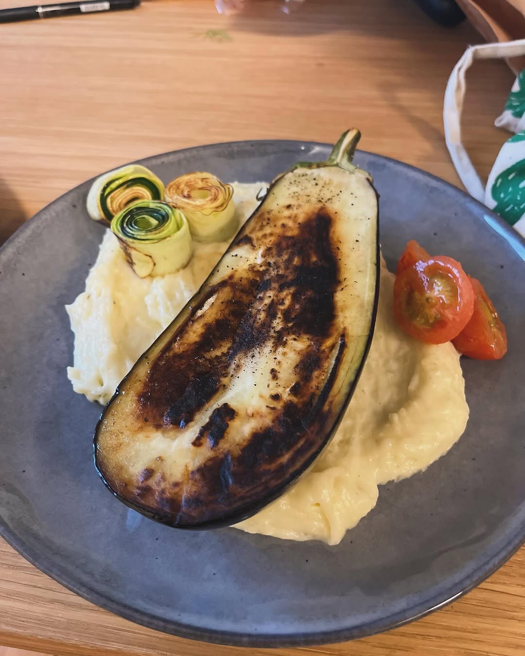 Charred whole eggplant on creamy mash with zucchini rolls and cherry tomatoes