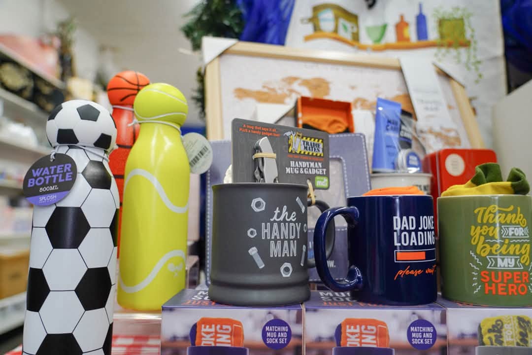 Shelf of gift mugs and sports-themed drink bottles