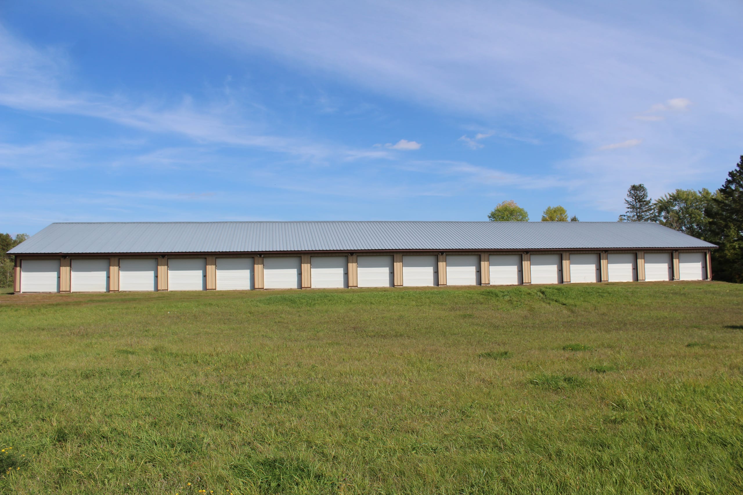 Long row of Splitrock Storage units with white roll-up doors and grey metal roof