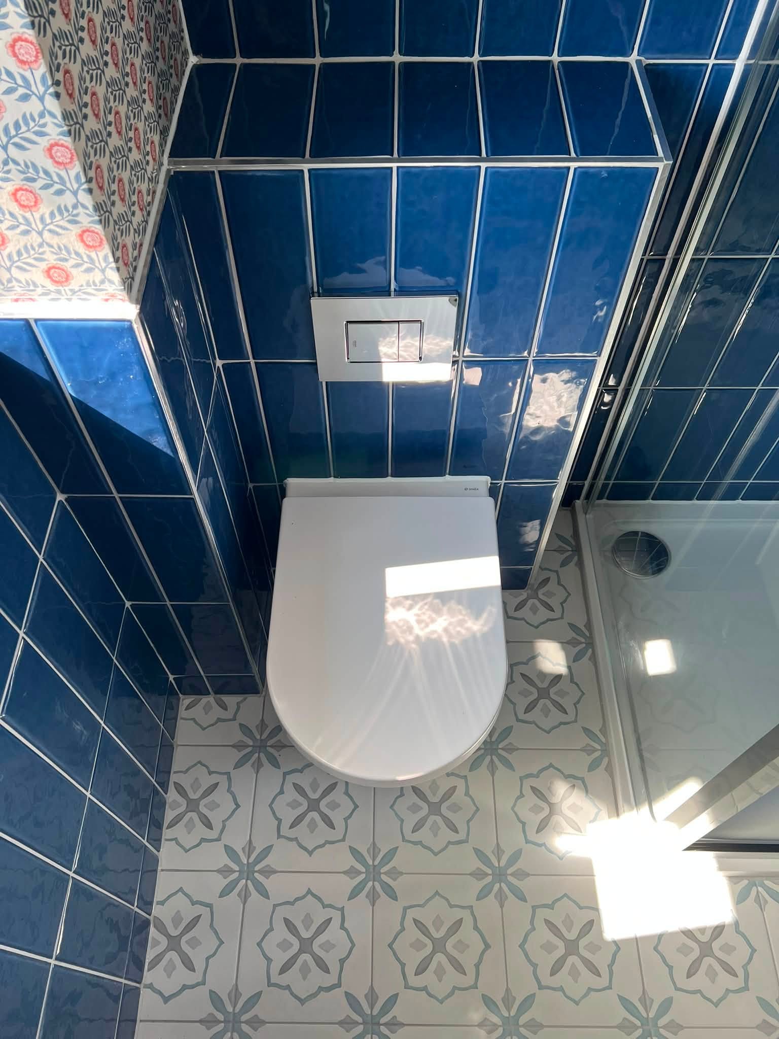 Wall-hung toilet with blue tiles and decorative patterned floor