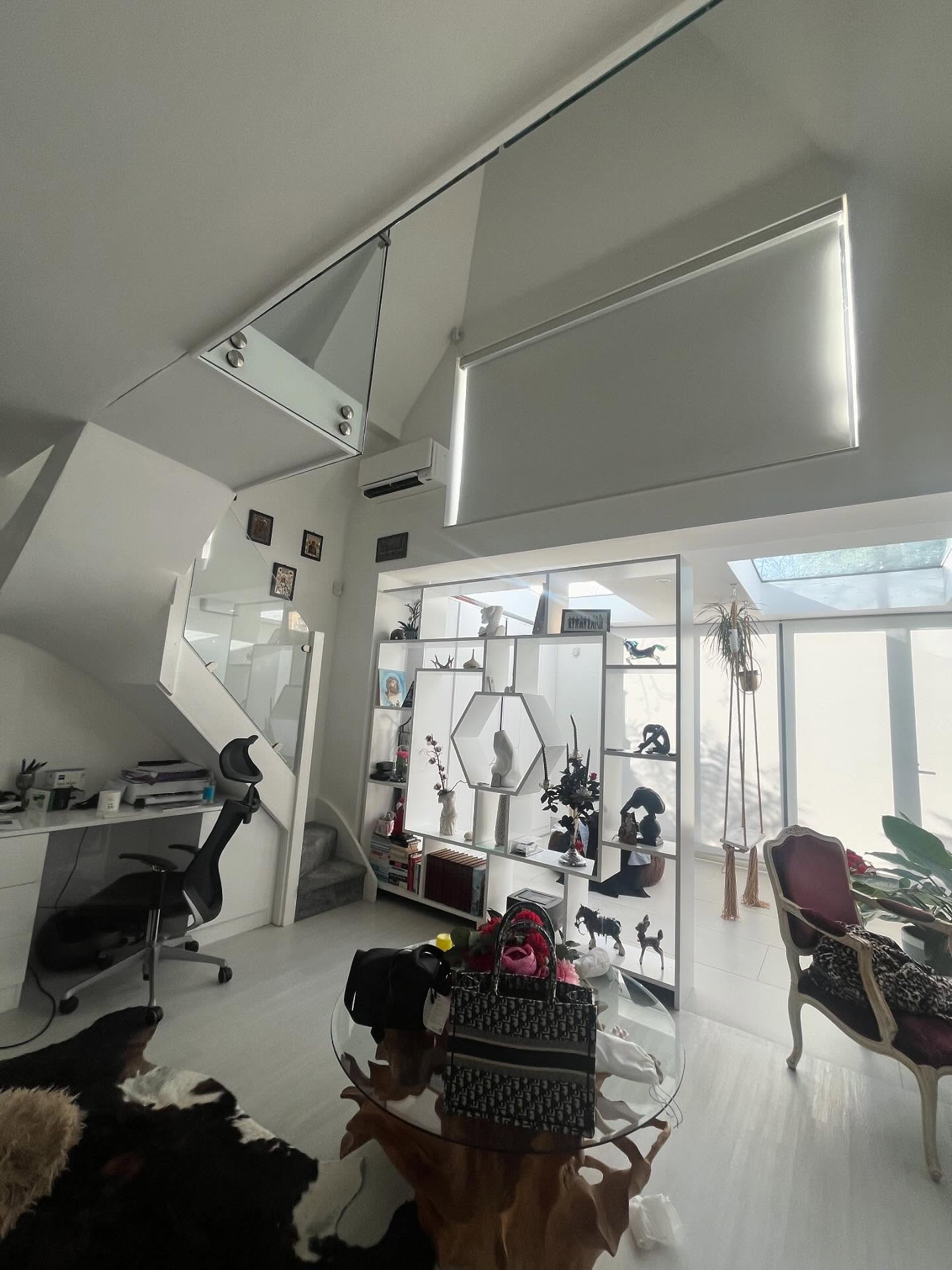Wall-mounted split system air conditioner installed high on the wall of a light-filled modern open-plan space