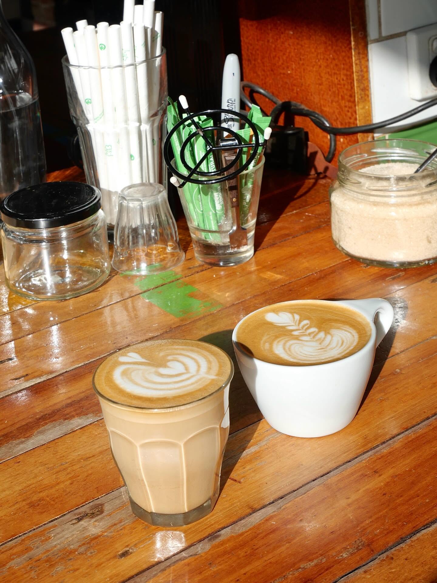 Latte art in two coffee cups on a wooden cafe table at Milking It