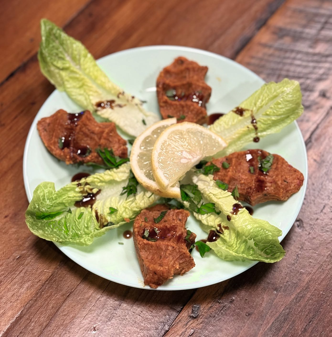 Plated bites on cos lettuce leaves with lemon wedges and herbs