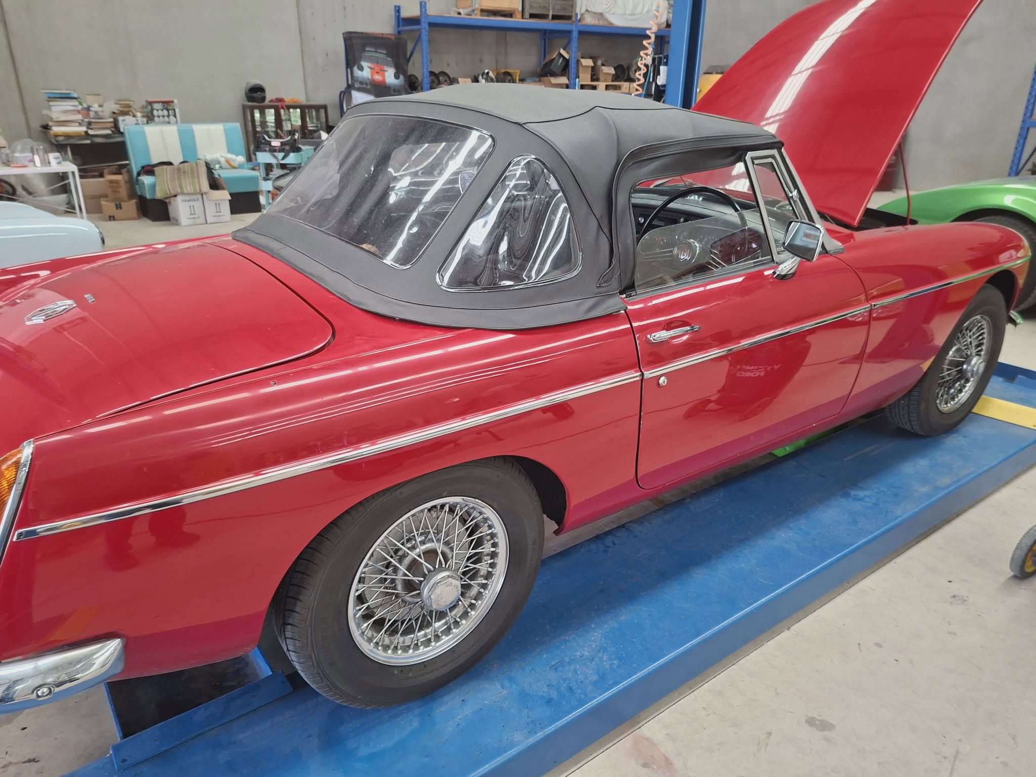 Finished red MGB roadster with black soft-top on wheel alignment ramp — April Motors Classic Car Garage