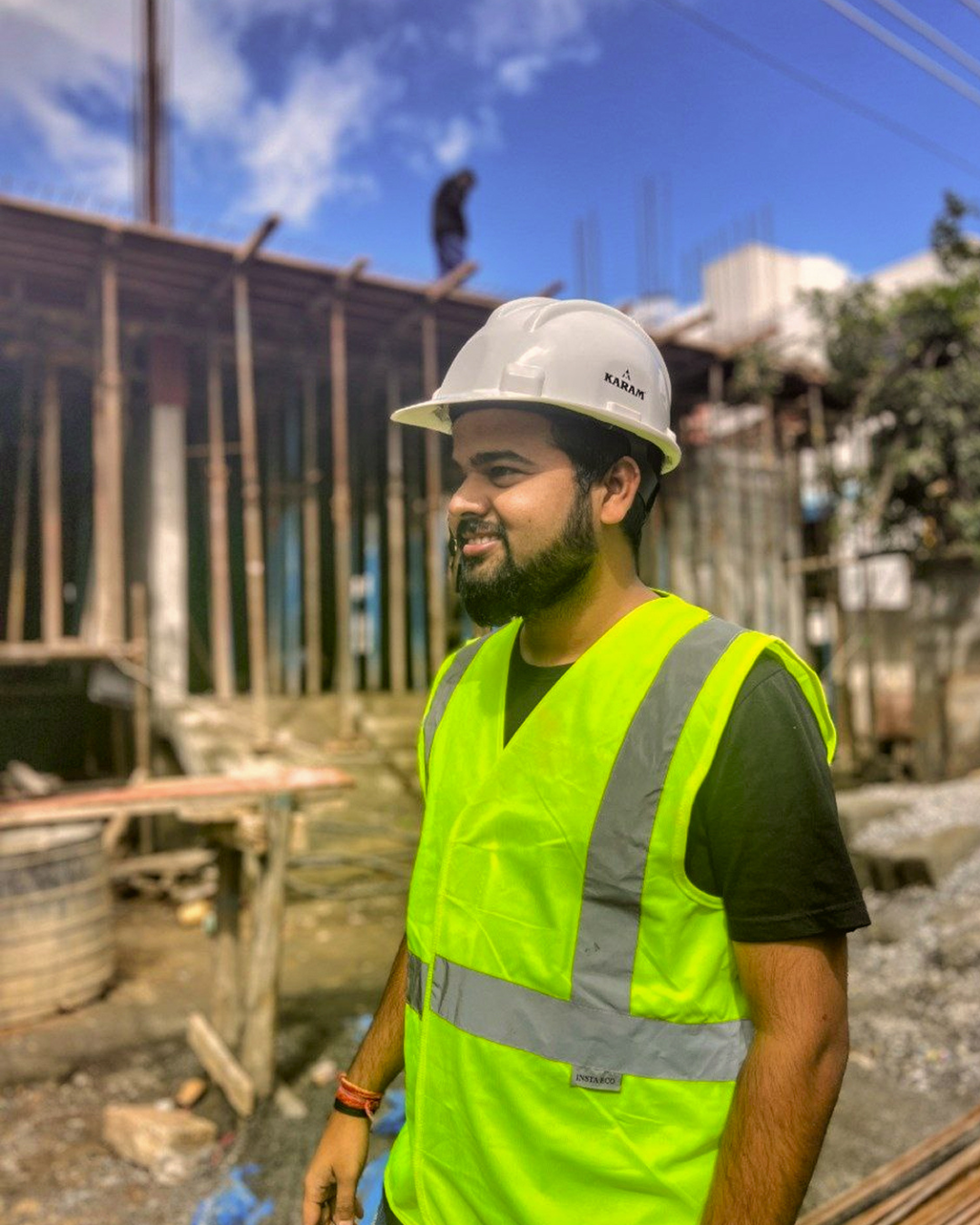 Devendra Kumar — Civil Engineer and founder of ConstructDocs, wearing a white KARAM safety helmet and neon green hi-vis vest at a construction site