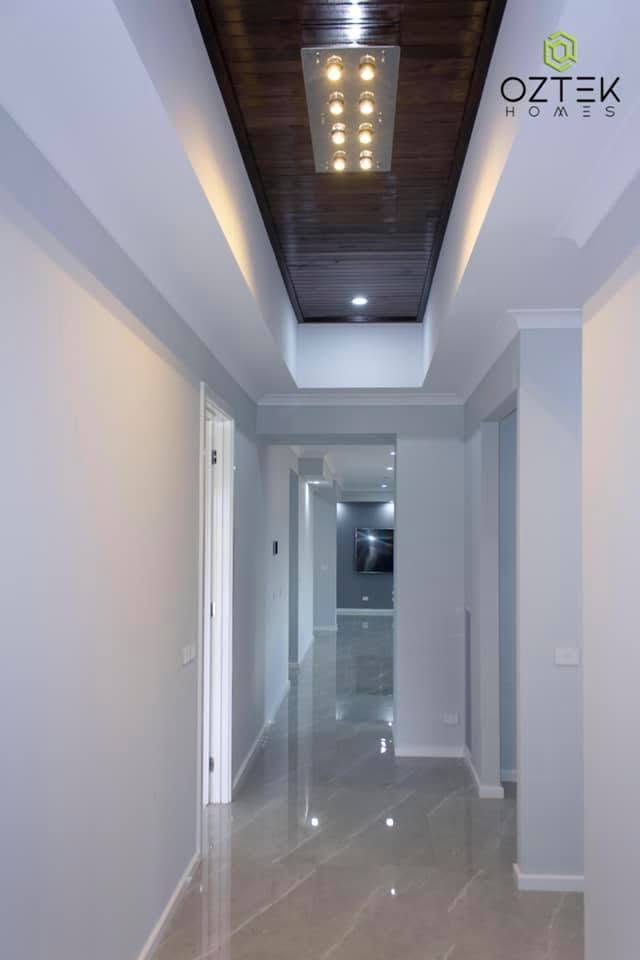 Elegant hallway with decorative timber ceiling panel and crystal chandelier