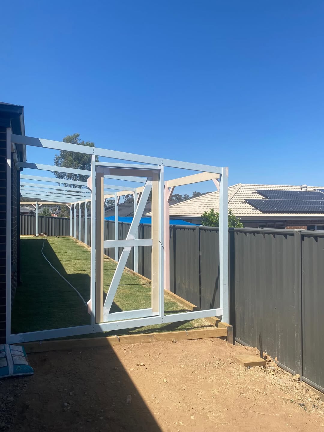 White steel garage frame being erected on a suburban block
