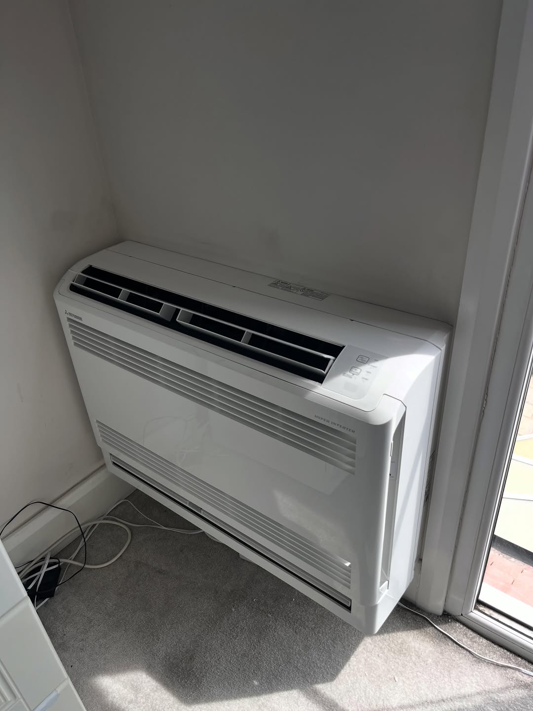 Floor-standing console air conditioning unit installed in a corner of a residential room