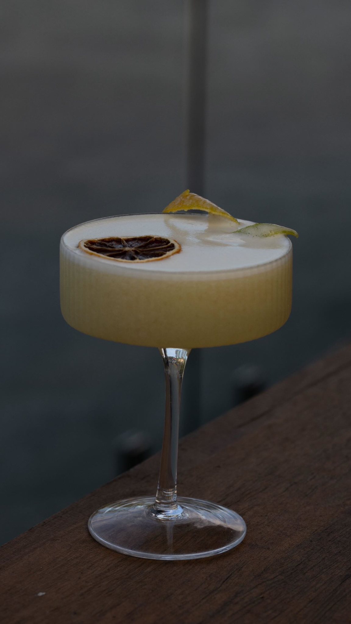 Elegant cocktail beverage in a coupe glass on a wooden table at Little Elm Cafe