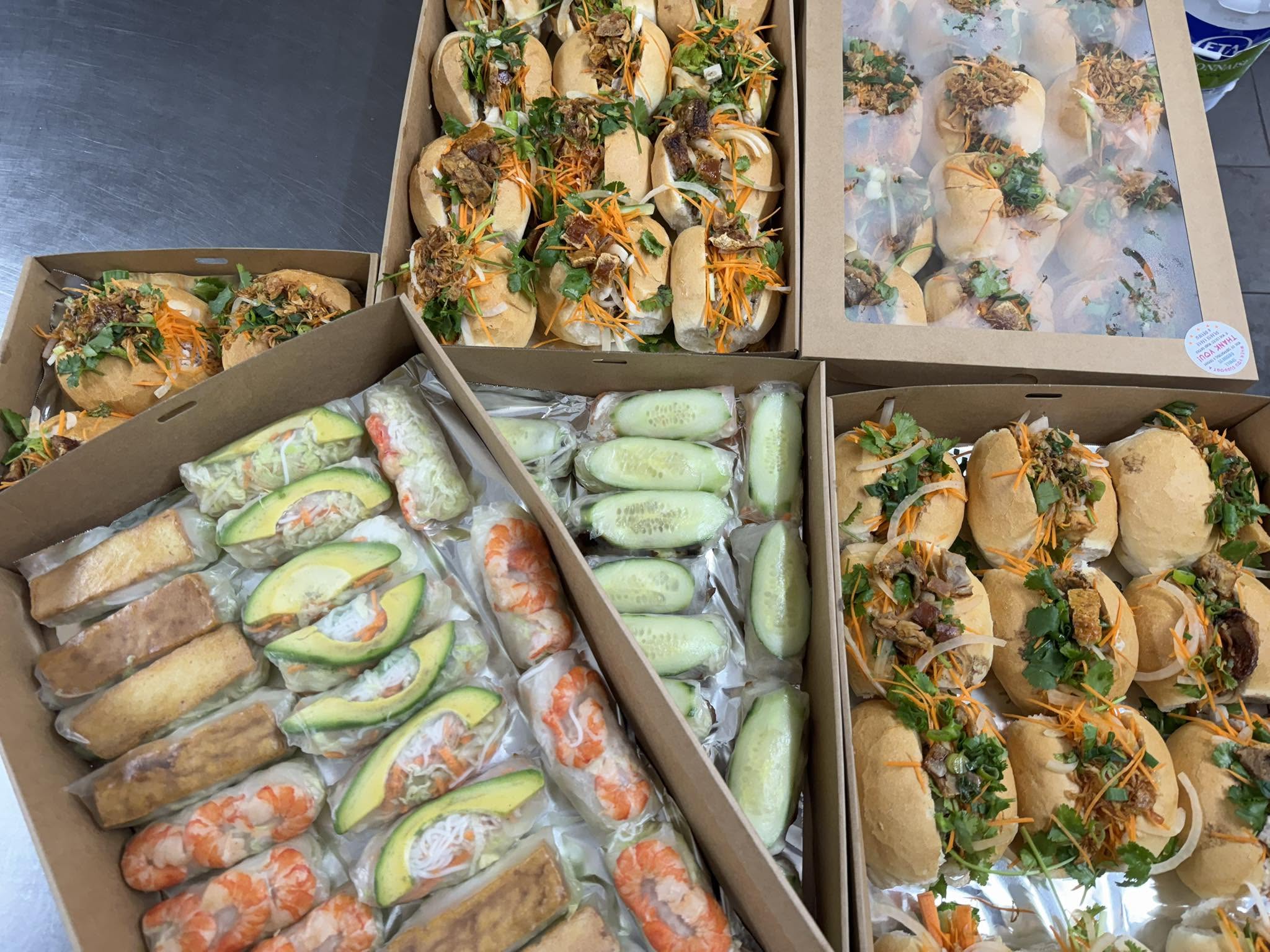 Takeaway boxes filled with Vietnamese bánh mì rolls and rice paper rolls