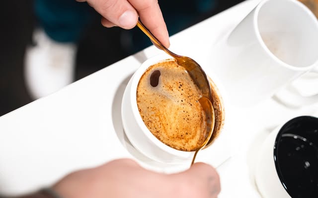 Close-up of a freshly brewed espresso being stirred with a gold spoon