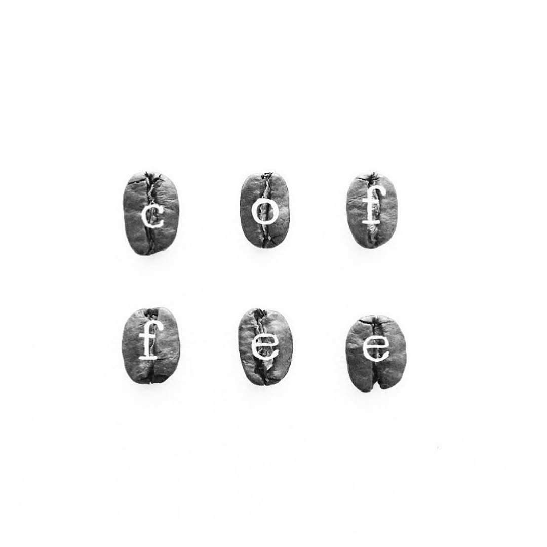 Artistic arrangement of six coffee beans spelling the word coffee