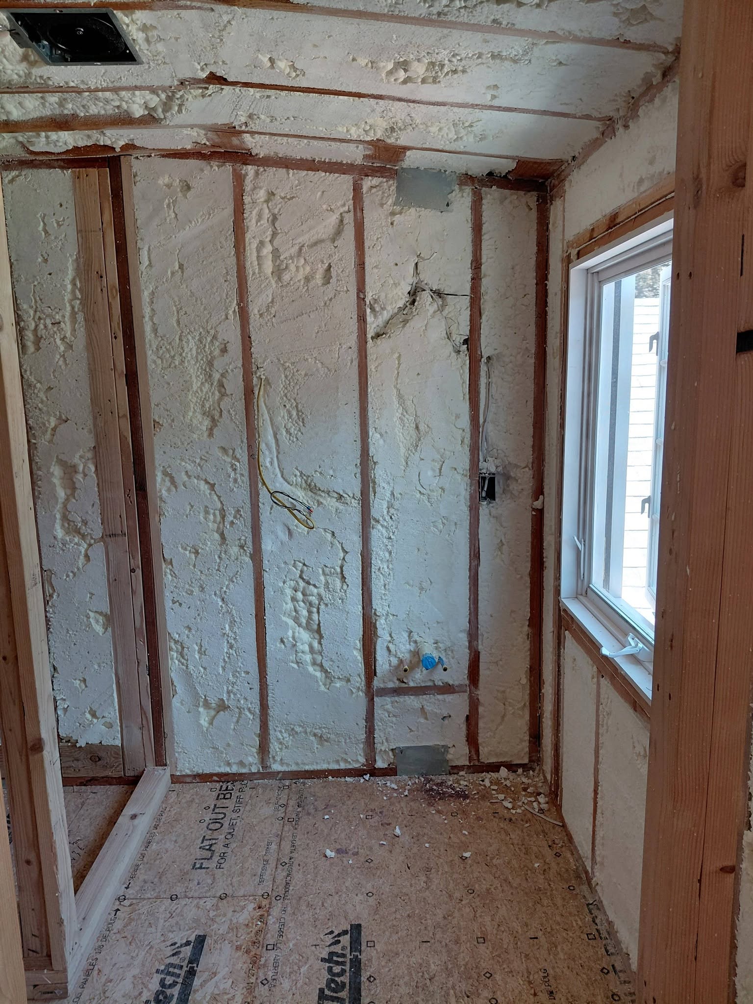 Spray foam insulated walls and wiring rough-in inside a timber-framed room under construction