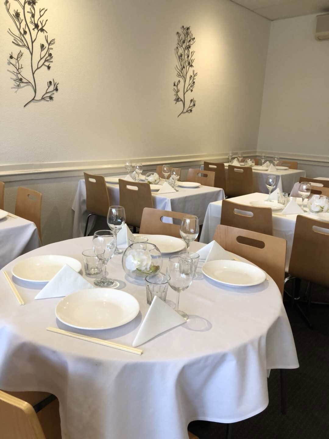 Painted Lantern dining room — round tables set with white linen, glasses and chopsticks