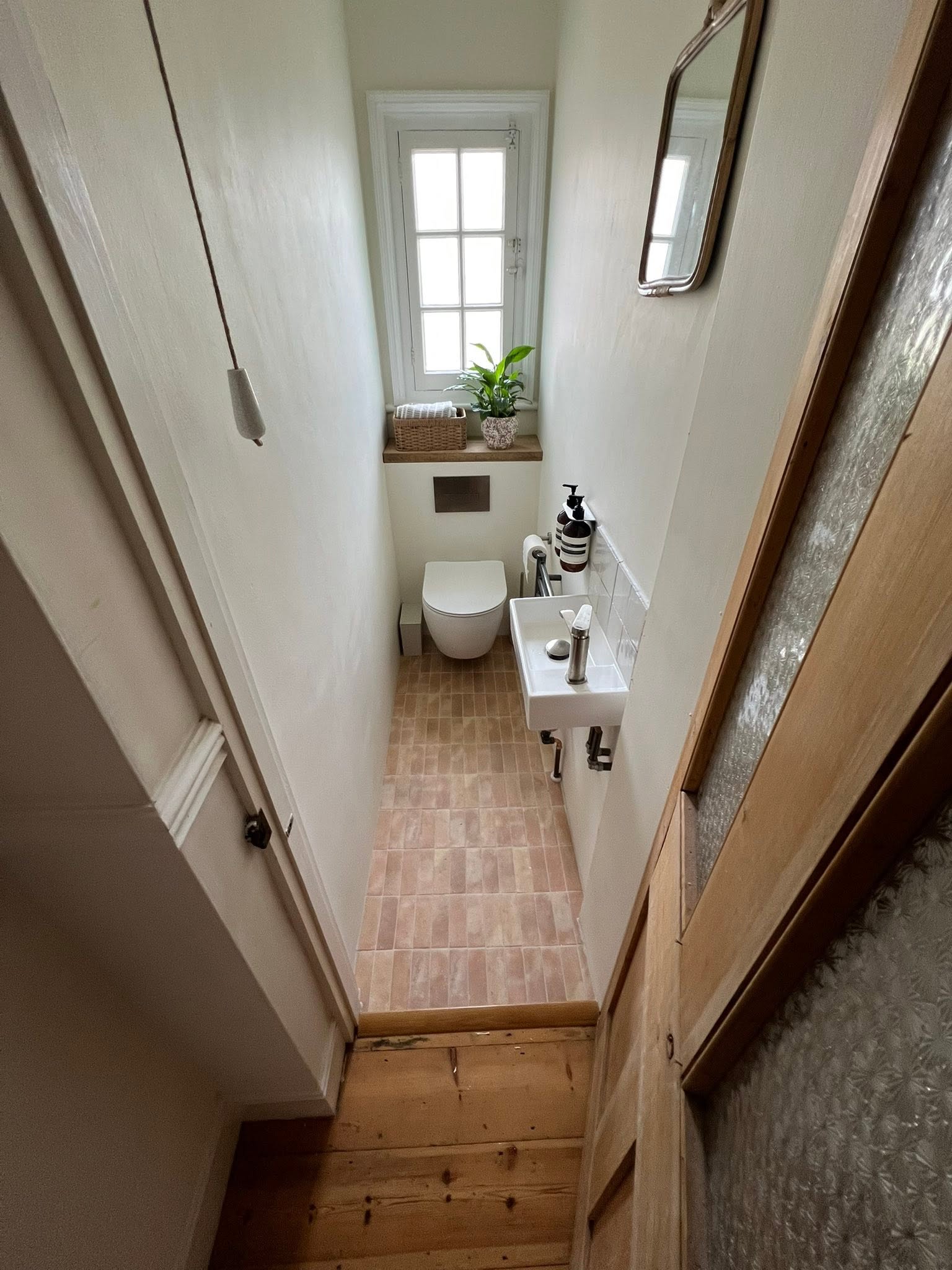 Compact powder room with terracotta floor tiles, wall-hung toilet and small sink