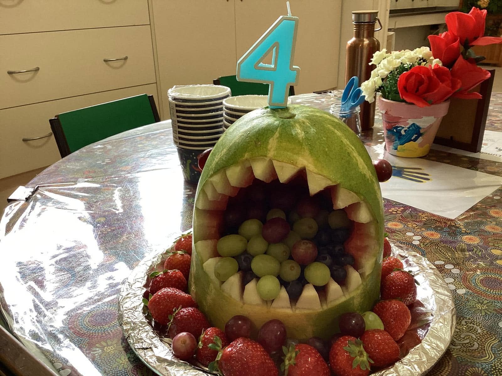 Creative fruit arrangement made by children at Dandenong North Preschool — a watermelon carved into a playful shark shape filled with fresh fruit