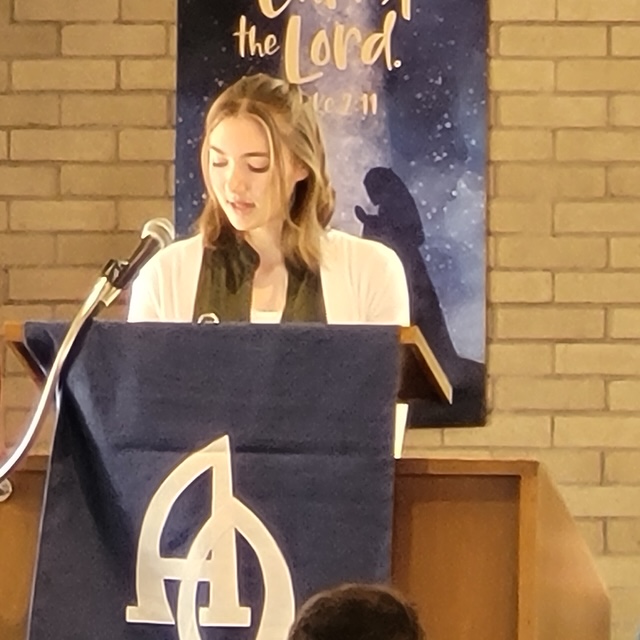 A young woman reading the Christmas Scripture at the lectern during a Christmas Eve service
