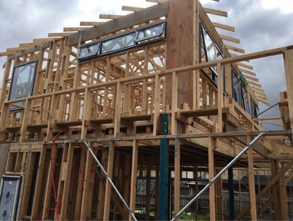 Timber-framed residential home under construction with roof trusses in place