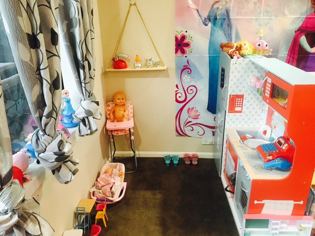 Cosy imaginative play corner with toy kitchen, dress-up items, and colourful wall decals