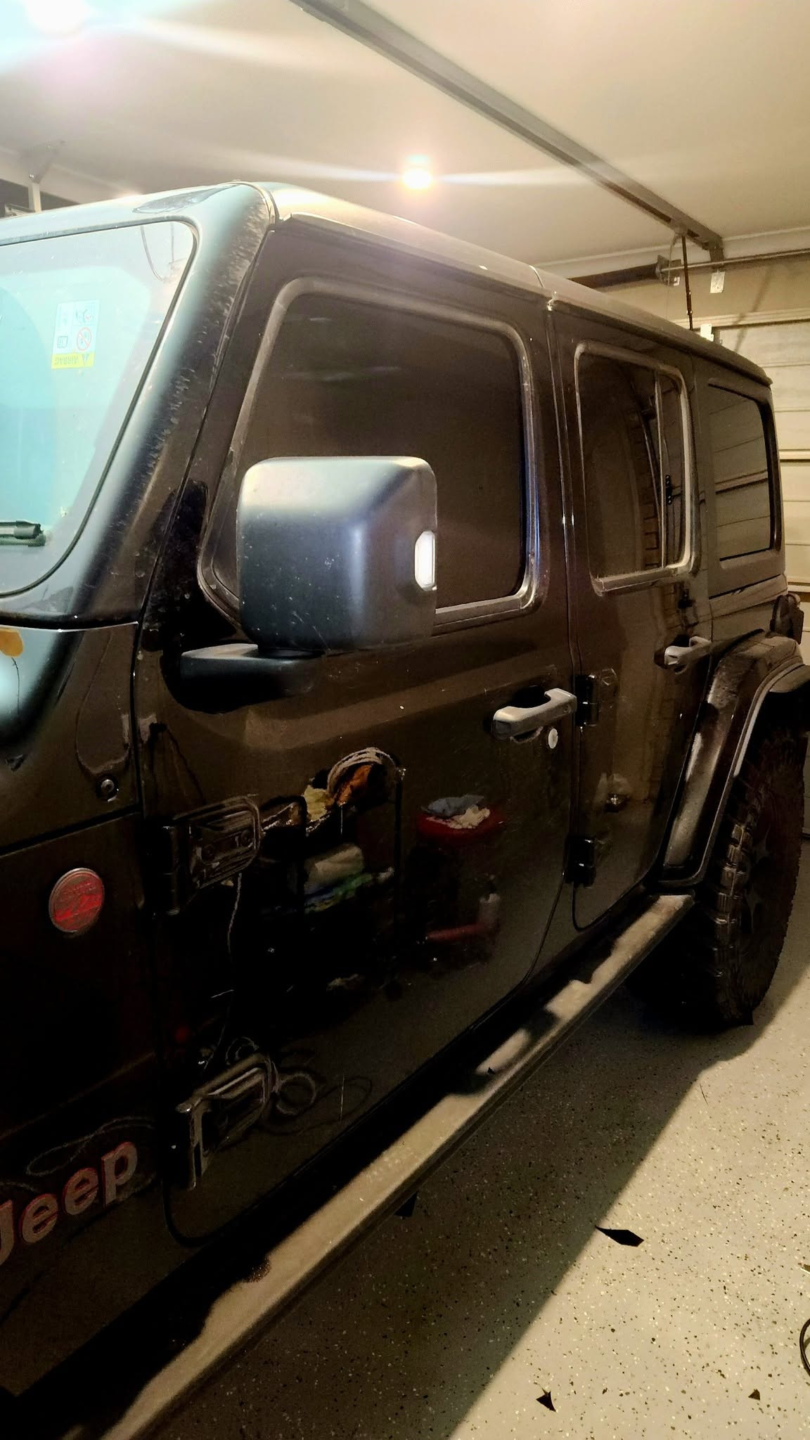 Black four-door Jeep Wrangler with tinted rear windows parked in a garage