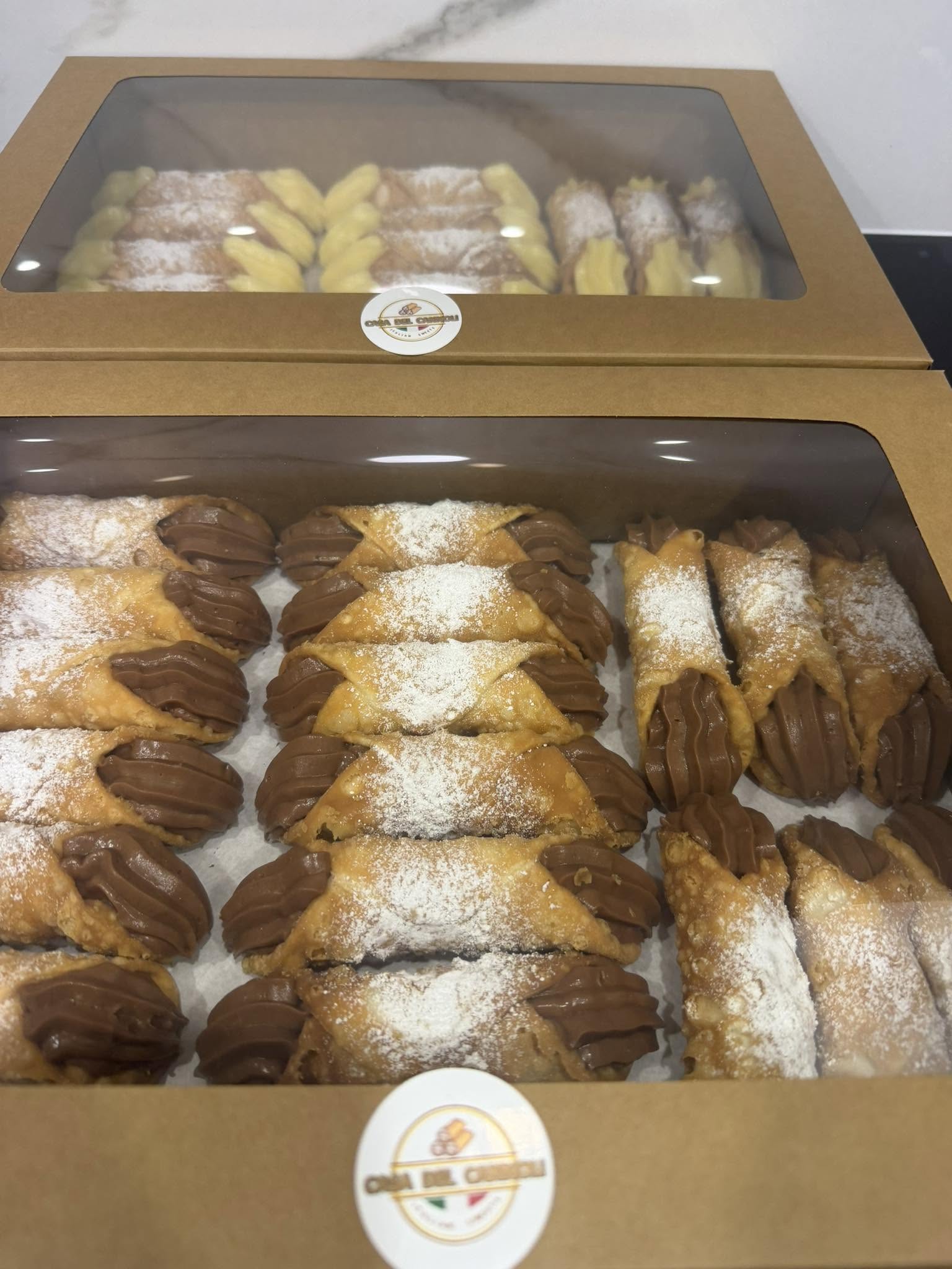 Pistachio cannoli on a white plate covered in icing sugar